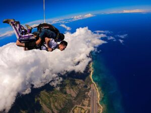 Tandem skydivers free-falling over the Hawaiian coast.