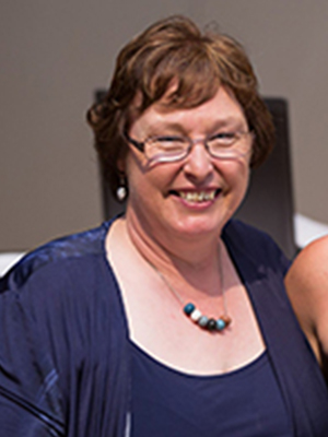 A photo of Mandy Basson wearing a dark blue dress and smiling.